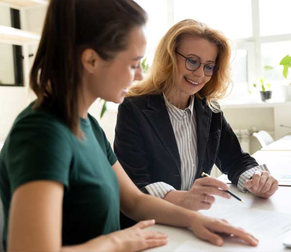 Une avocate positive parle avec une cliente. En discutant avec la jeune femme, elle souriait chaleureusement.